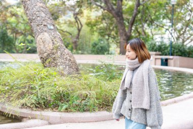 20 'li yaşlarda Çinli bir kadın kışın soğuk olan Hong Kong' da, Tsim Sha Tsui 'de bir parkta vakit geçiriyor.