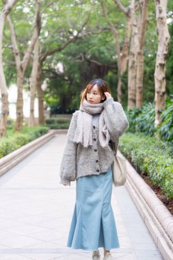 20 'li yaşlarda Çinli bir kadın kışın soğuk olan Hong Kong' da, Tsim Sha Tsui 'de bir parkta vakit geçiriyor.