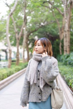 20 'li yaşlarda Çinli bir kadın kışın soğuk olan Hong Kong' da, Tsim Sha Tsui 'de bir parkta vakit geçiriyor.