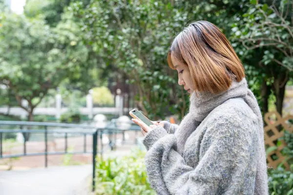 20 'li yaşlarda Çinli bir kadın kışın soğuk olan Hong Kong' da, Tsim Sha Tsui 'de bir parkta vakit geçiriyor.