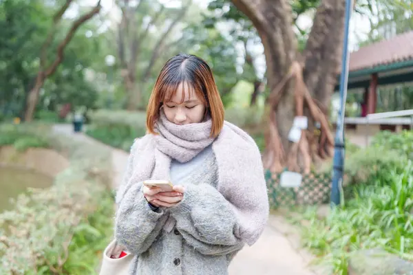 20 'li yaşlarda Çinli bir kadın kışın soğuk olan Hong Kong' da, Tsim Sha Tsui 'de bir parkta vakit geçiriyor.