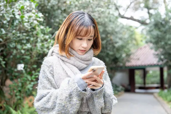 20 'li yaşlarda Çinli bir kadın kışın soğuk olan Hong Kong' da, Tsim Sha Tsui 'de bir parkta vakit geçiriyor.