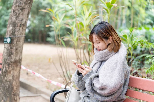 20 'li yaşlarda Çinli bir kadın kışın soğuk olan Hong Kong' da, Tsim Sha Tsui 'de bir parkta vakit geçiriyor.