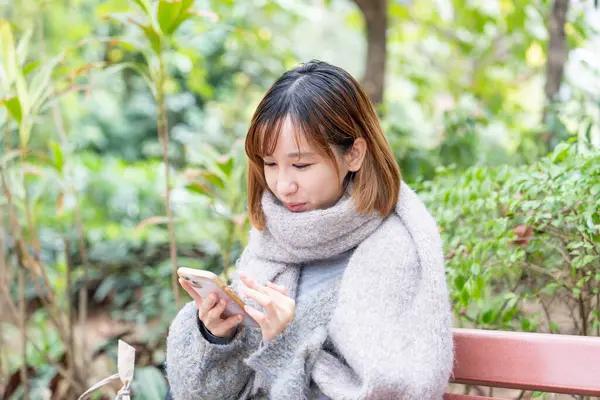 20 'li yaşlarda Çinli bir kadın kışın soğuk olan Hong Kong' da, Tsim Sha Tsui 'de bir parkta vakit geçiriyor.