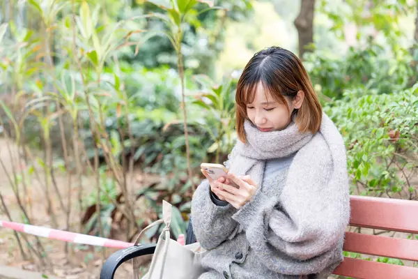 20 'li yaşlarda Çinli bir kadın kışın soğuk olan Hong Kong' da, Tsim Sha Tsui 'de bir parkta vakit geçiriyor.
