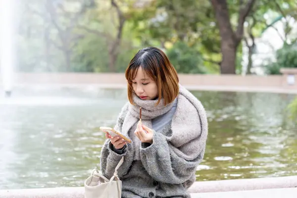 20 'li yaşlarda Çinli bir kadın kışın soğuk olan Hong Kong' da, Tsim Sha Tsui 'de bir parkta vakit geçiriyor.