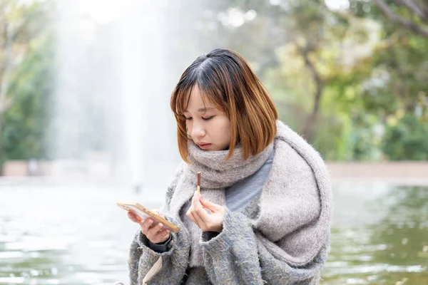 20 'li yaşlarda Çinli bir kadın kışın soğuk olan Hong Kong' da, Tsim Sha Tsui 'de bir parkta vakit geçiriyor.