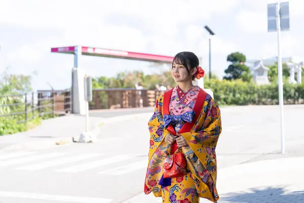 A young Japanese woman in her 20s in Ryukyu dress at a place with a view of the sea on Umikaji Terrace in Senaga, Tomigusuku City, Okinawa Prefecture