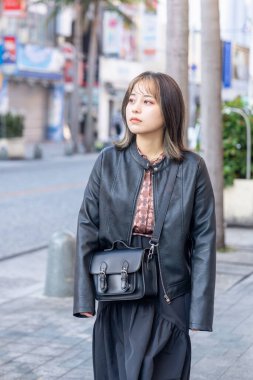 Okinawa bölgesinden 20 'li yaşlarda genç bir kadın soğuk bir kış günü Naha City, Okinawa' da Kokusai-dori Caddesi 'nde yürüyor.