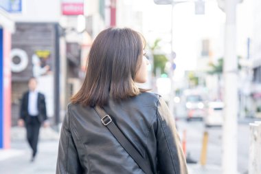 Okinawa bölgesinden 20 'li yaşlarda genç bir kadın soğuk bir kış günü Naha City, Okinawa' da Kokusai-dori Caddesi 'nde yürüyor.