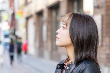 Okinawa bölgesinden 20 'li yaşlarda genç bir kadın soğuk bir kış günü Naha City, Okinawa' da Kokusai-dori Caddesi 'nde yürüyor.