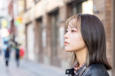 Okinawa bölgesinden 20 'li yaşlarda genç bir kadın soğuk bir kış günü Naha City, Okinawa' da Kokusai-dori Caddesi 'nde yürüyor.