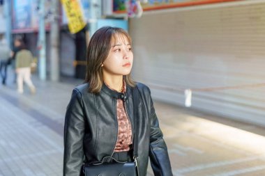 Okinawa bölgesinden 20 'li yaşlarda genç bir kadın soğuk bir kış günü Naha City, Okinawa' da Kokusai-dori Caddesi 'nde yürüyor.