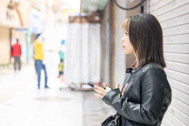 Okinawa bölgesinden 20 'li yaşlarda genç bir kadın soğuk bir kış günü Naha City, Okinawa' da Kokusai-dori Caddesi 'nde yürüyor.
