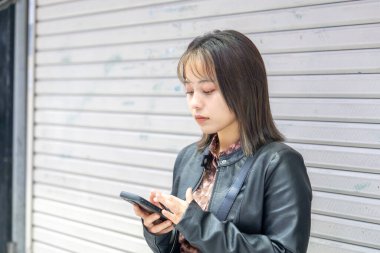 Okinawa bölgesinden 20 'li yaşlarda genç bir kadın soğuk bir kış günü Naha City, Okinawa' da Kokusai-dori Caddesi 'nde yürüyor.