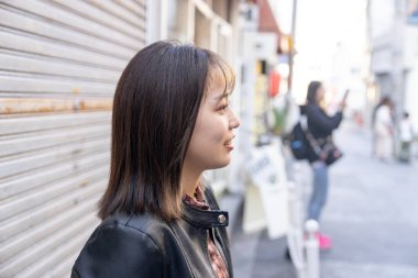Okinawa bölgesinden 20 'li yaşlarda genç bir kadın soğuk bir kış günü Naha City, Okinawa' da Kokusai-dori Caddesi 'nde yürüyor.