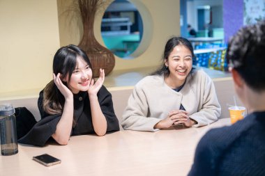 Tayvanlı ve Asyalı üç üniversite öğrencisi Da 'an Bölgesi, Tayvan' da bir üniversite kafeteryasında konuşuyorlar.