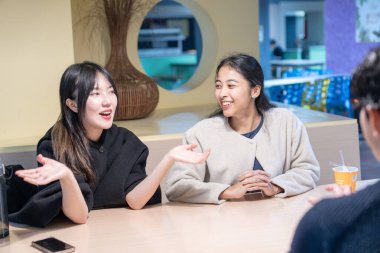 Tayvanlı ve Asyalı üç üniversite öğrencisi Da 'an Bölgesi, Tayvan' da bir üniversite kafeteryasında konuşuyorlar.