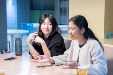 Tayvanlı ve Asyalı üç üniversite öğrencisi Da 'an Bölgesi, Tayvan' da bir üniversite kafeteryasında konuşuyorlar.