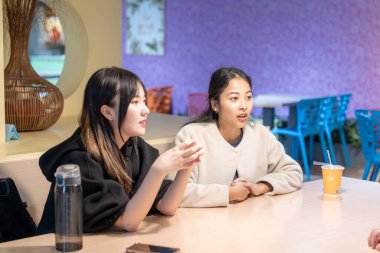 Tayvanlı ve Asyalı üç üniversite öğrencisi Da 'an Bölgesi, Tayvan' da bir üniversite kafeteryasında konuşuyorlar.