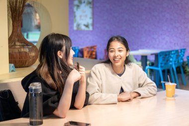 Tayvanlı ve Asyalı üç üniversite öğrencisi Da 'an Bölgesi, Tayvan' da bir üniversite kafeteryasında konuşuyorlar.