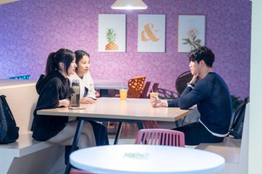 Tayvanlı ve Asyalı üç üniversite öğrencisi Da 'an Bölgesi, Tayvan' da bir üniversite kafeteryasında konuşuyorlar.