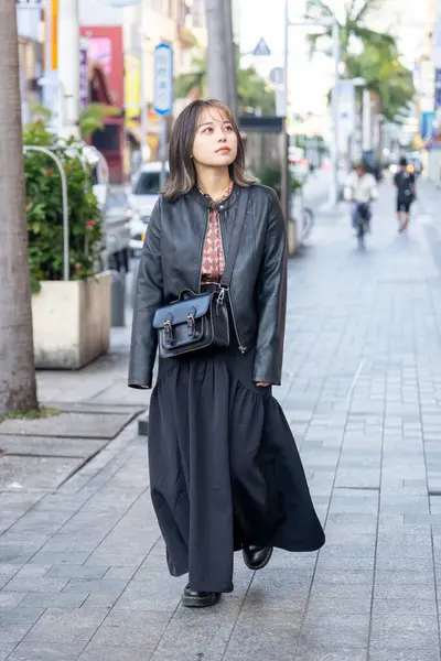 Okinawa bölgesinden 20 'li yaşlarda genç bir kadın soğuk bir kış günü Naha City, Okinawa' da Kokusai-dori Caddesi 'nde yürüyor.
