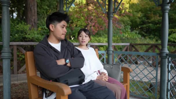 愛知県名古屋市中区の公園で座って話している20代の男女のスローモーションビデオ — ストック動画