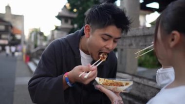 20 'li yaşlarında genç bir Japon çift Nagoya City, Aichi' de takoyaki yiyorlar.
