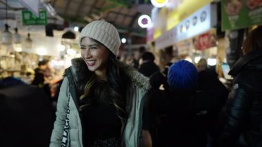 20 'li yaşlarda Filipinli bir kadının Seul, Güney Kore' de geleneksel bir pazarda yürüyüşünün yavaş çekim videosu.