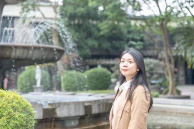 Tayvanlı 20 'li yaşlarda bir kadın Songshan Wenso Park, Xinyi Bölgesi, Taipei Şehri, Tayvan' da bir parkta vakit geçiriyor.