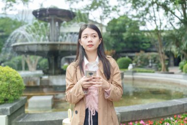 Tayvanlı 20 'li yaşlarda bir kadın Songshan Wenso Park, Xinyi Bölgesi, Taipei Şehri, Tayvan' da bir parkta vakit geçiriyor.