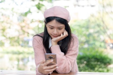 Tayvanlı bir kadın 20 'li yaşlarda Matsuyama Wenso Park, Xinyi Mahallesi, Taipei Şehri, Tayvan' da bir parkta oturuyor.