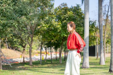 20 'li yaşlarda Asyalı bir kadın, Hong Kong, Kowloon' da deniz kenarında bir parkta köpeğiyle oynuyor.