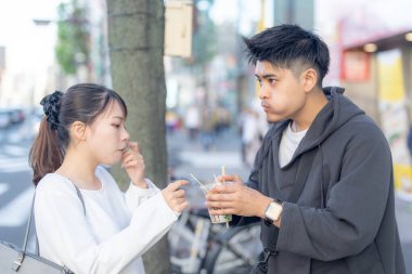20 'li yaşlarda Japon bir çift Nagoya City, Aichi' de kızarmış sokak yemeği yiyor. 
