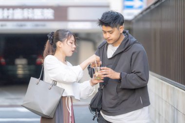 20 'li yaşlarda Japon bir çift Nagoya City, Aichi' de kızarmış sokak yemeği yiyor. 