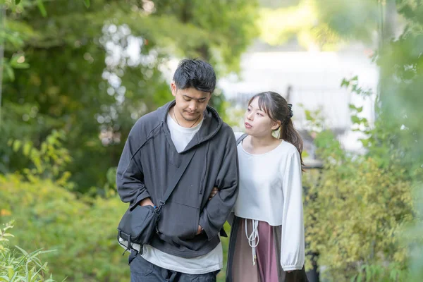 A Japanese couple of young men and women in their 20s walking in a park in Nagoya City, Aichi Prefecture