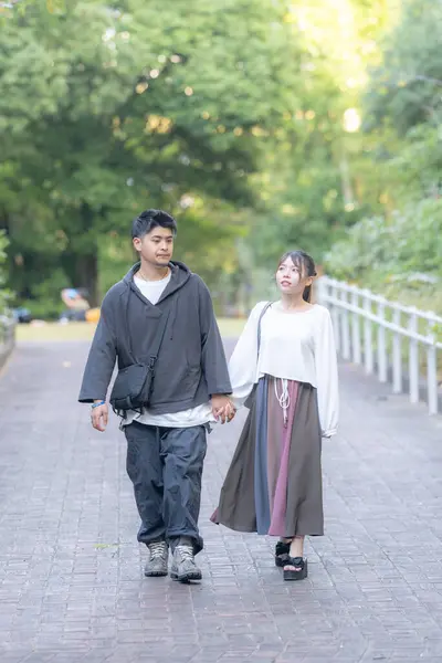 A Japanese couple of young men and women in their 20s walking in a park in Nagoya City, Aichi Prefecture