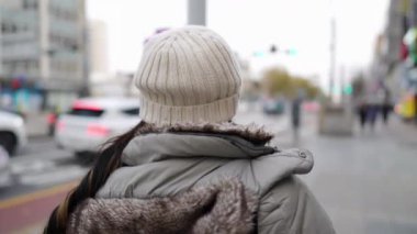 20 'li yaşlarda genç bir Filipinli kadının soğuk bir kış gününde Güney Kore, Seul' de yürüyüşünün yavaş çekim videosu.