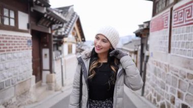 20 'li yaşlarda genç bir Filipinli kadının soğuk bir kış günü Hanok Köyü, Kuzey Köyü, Seul' de yürüyüş yaptığı ağır çekim videosu.