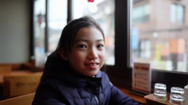 Aç Koreli genç kız akıllı telefonunu kullanıyor ve Güney Kore, Seul 'de bir restoranda yemek beklerken bekliyor.