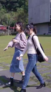 Taipei, Tayvan 'da bir üniversite kampüsünde konuşan iki genç Tayvanlı kız öğrencinin dikey videosu. 