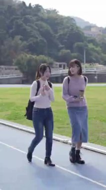 Taipei, Tayvan 'da bir üniversite kampüsünde konuşan iki genç Tayvanlı kız öğrencinin dikey videosu. 