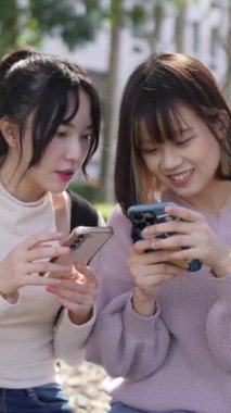 Tayvan, Tayvan 'da bir üniversite kampüsünde mutlu bir şekilde konuşan iki genç Tayvanlı kız öğrencinin dikey videosu.