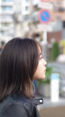 Okinawa 'nın Naha şehrinde turistik bir yer olan Kokusai Caddesi' nde 20 'li yaşlarda genç bir Japon kadının yürüdüğü dikey video.