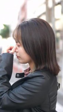 Okinawa 'nın Naha şehrinde turistik bir yer olan Kokusai Caddesi' nde 20 'li yaşlarda genç bir Japon kadının yürüdüğü dikey video.