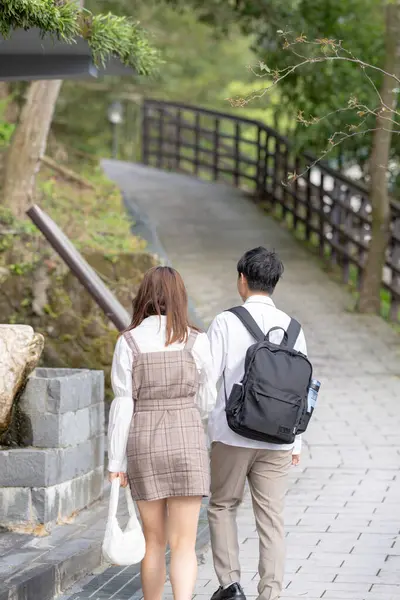 stock image A young Taiwanese male and female couple in their 20s are taking a walk while talking happily in the mountain of Maokong, a tourist destination in Taiwan.