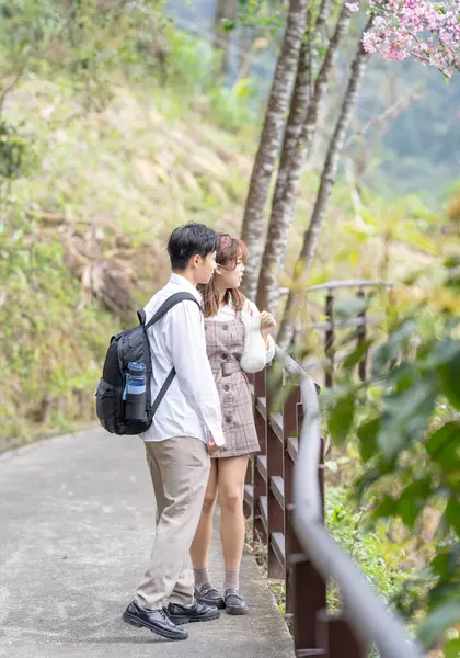 A young Taiwanese male and female couple in their 20s are taking a walk while talking happily in the mountain of Maokong, a tourist destination in Taiwan.