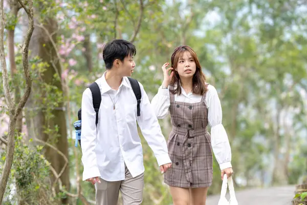 A young Taiwanese male and female couple in their 20s are taking a walk while talking happily in the mountain of Maokong, a tourist destination in Taiwan.