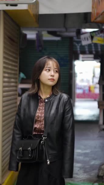 日本冲绳一位20多岁的年轻女子20多岁时在冲绳Naha市Kokusai Dori街附近的一条购物街上散步的慢动作垂直录像 — 图库视频影像